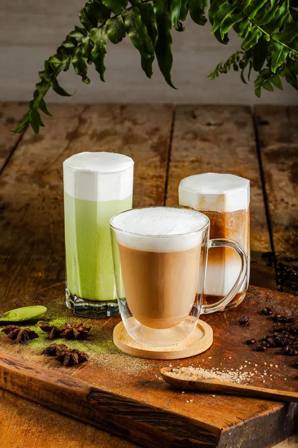 Layered coffee and matcha drinks styled on a cafe table